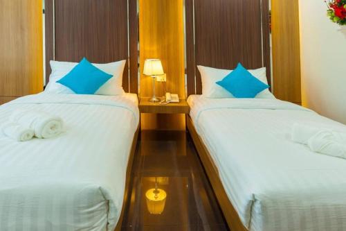 two beds with blue pillows in a hotel room at Thanburi Hotel in Udon Thani