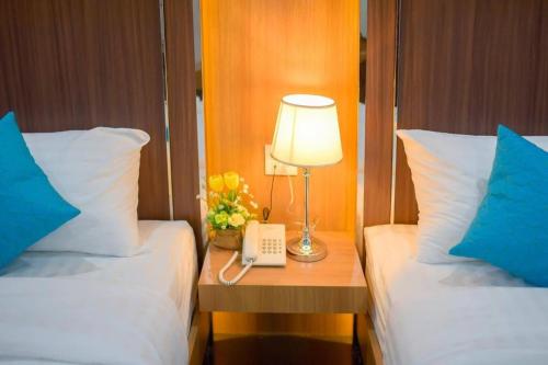 a hotel room with two beds and a lamp on a table at Thanburi Hotel in Udon Thani