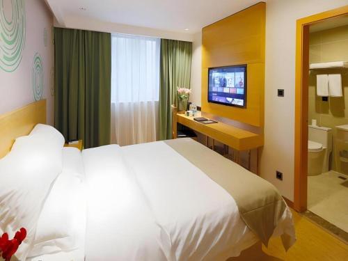 a bedroom with a bed and a bathroom with a television at GreenTree Inn Shanghai Railway Station Macao Road in Shanghai
