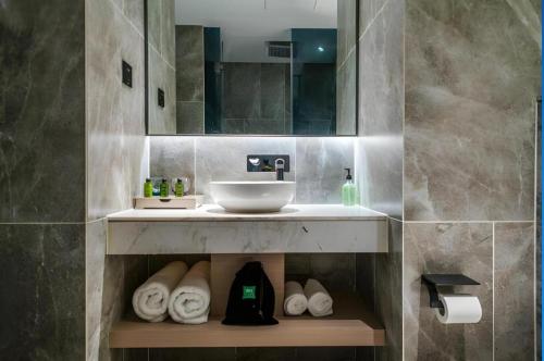 a bathroom with a sink and a mirror and towels at ibis Styles Yangzhou Baixiang Rd Hotel in Yangzhou