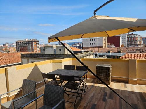 a table and chairs on a balcony with an umbrella at Ático Jovellanos in Gijón