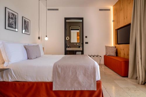 a bedroom with a large white bed and a couch at Essenza Relais Contemporaneo in Cisternino