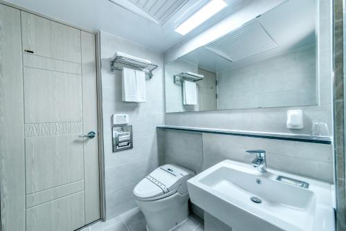 a white bathroom with a toilet and a sink at The Stay Century Hotel in Jeju