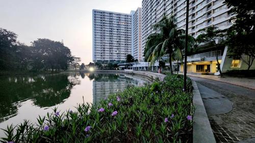 a river in a city with buildings and flowers at Trivium Terrace Apartment Lippo Cikarang EJIP -Min Stay 3 Nights- in Bekasi