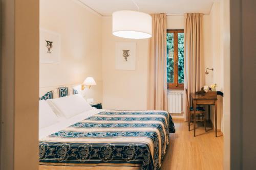 a bedroom with a bed and a desk and a window at Hotel San Luca in Cortona