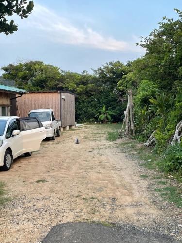 two cars parked in a dirt lot with trees at BIRD-LOGG Amami in Amami