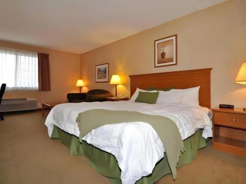 a hotel room with a large bed with white sheets at Best Western Rama Inn in Ephrata