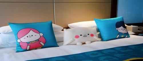 a bed with three pillows with hello kitty on it at Gaosu New Century Hotel International Anhui in Hefei