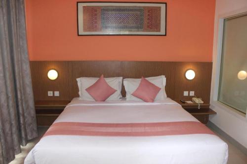 a bedroom with a large white bed with pink pillows at Pomelotel Patra Kuningan Jakarta in Jakarta