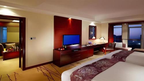 a hotel room with a bed and a television at Gaosu New Century Hotel International Anhui in Hefei