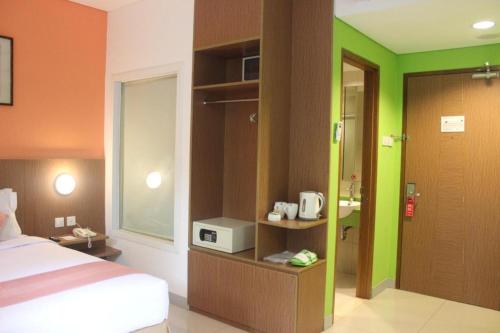 a hotel room with a bed and green and orange walls at Pomelotel Patra Kuningan Jakarta in Jakarta