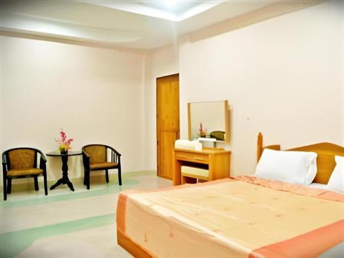 a bedroom with a bed and a desk and chairs at 107 Tower Hotel Nan in Nan