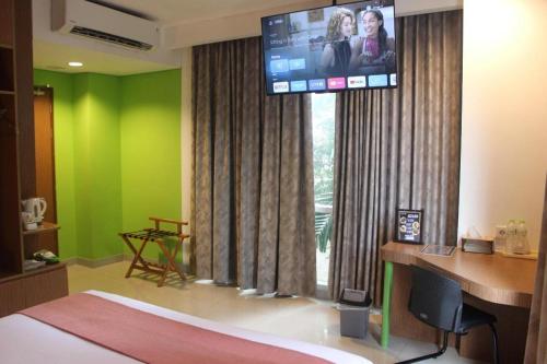 a bedroom with green walls and a flat screen tv at Pomelotel Patra Kuningan Jakarta in Jakarta