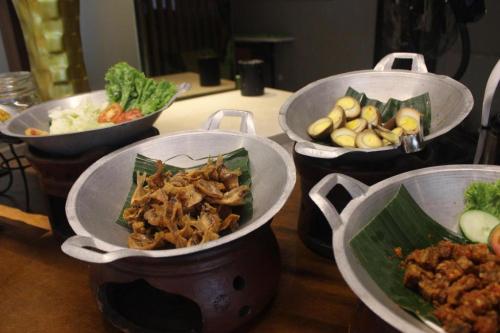 three pots of food on a table with vegetables at Pomelotel Patra Kuningan Jakarta in Jakarta
