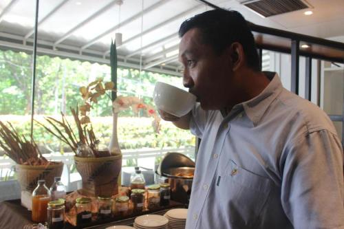 a man drinking from a cup of tea at Pomelotel Patra Kuningan Jakarta in Jakarta