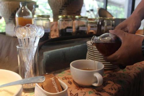 a person pouring coffee into a cup on a counter at Pomelotel Patra Kuningan Jakarta in Jakarta