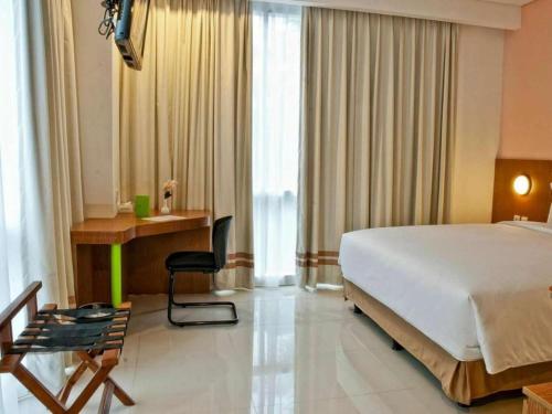 a bedroom with a large bed and a desk and a chair at Pomelotel Patra Kuningan Jakarta in Jakarta