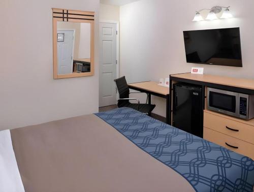 a hotel room with a bed and a desk and a tv at Econo Lodge Rochester I-90 & I-390 in Rochester