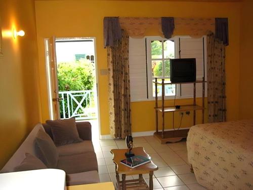 a living room with a couch and a tv at Gold Nugget Hotel in Negril