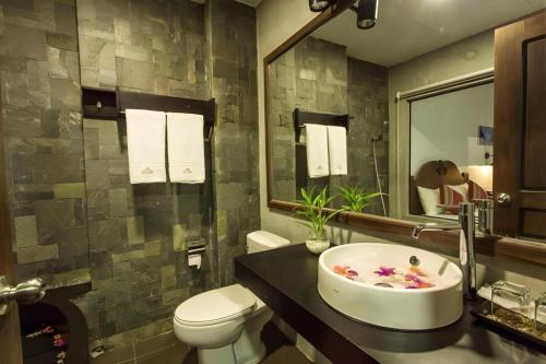 Un baño con lavabo, inodoro y espejo. en Yeak Loam Hotel, en Banlung