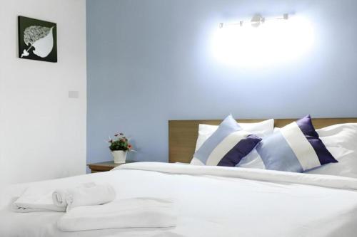 a white bed with purple and white pillows on it at Urban House 195 in Chiang Mai