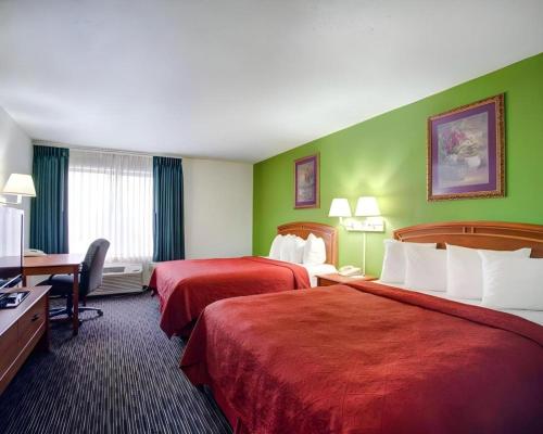 a hotel room with two beds and a desk at Quality Inn & Suites Airport in Austin