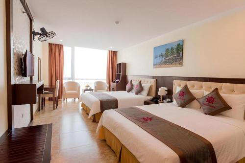 a hotel room with two beds and a desk at Thai An Hotel in Cửa Lò