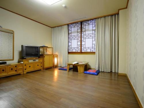 a living room with a flat screen tv and a table at Onyang Hot Spring Hotel in Asan