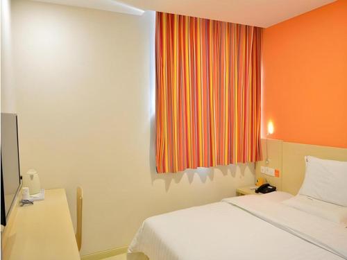- une chambre avec un lit et un mur orange dans l'établissement 7 Days Inn Beijing Niujie Street Metro Station Xuanwu Hospital, à Pékin