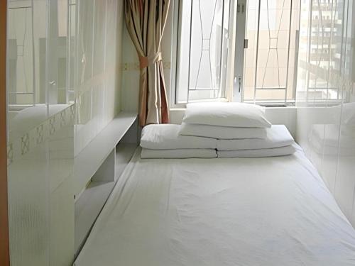 a white room with two beds in a window at New Mong Kok Guest House in Hong Kong