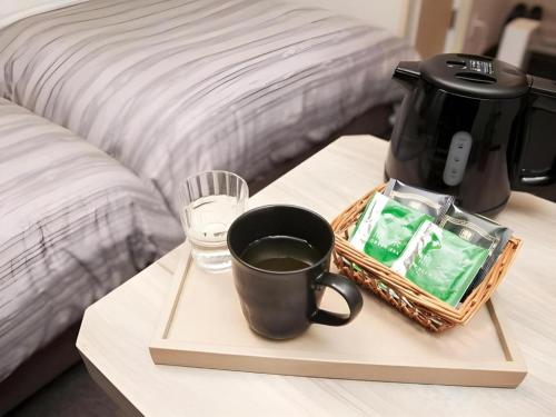a coffee maker and a tray with a cup of coffee at Hotel Route Inn Furukawa Ekimae in Osaki