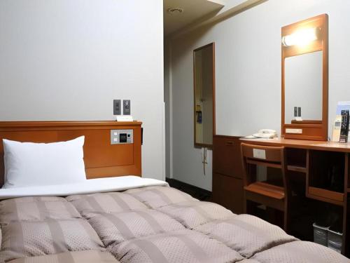 a bedroom with a bed and a dresser and a mirror at Hotel Route Inn Furukawa Ekimae in Osaki