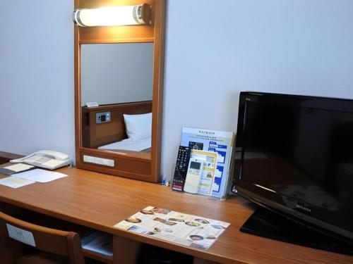 a wooden desk with a television and a mirror at Hotel Route Inn Furukawa Ekimae in Osaki