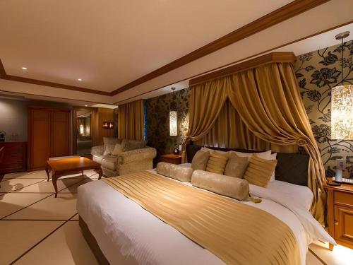 a bedroom with a large bed and a living room at Hotel Piena Kobe in Kobe