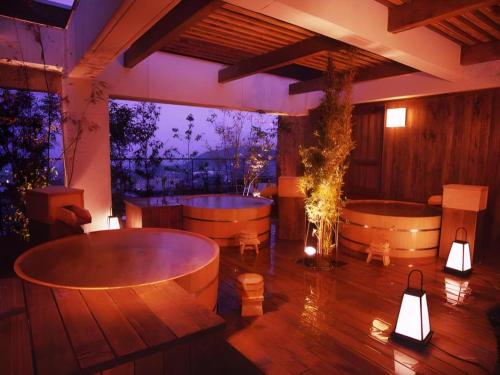 a room with two tubs and a table and lights at Kannawa Onsen Hotel Sansuikan in Beppu