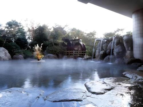 a pond of water with a train in the background at Kannawa Onsen Hotel Sansuikan in Beppu