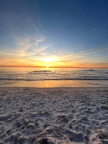 a sunset on a beach with the ocean at Premium Holidays Apartamenty przy plaży in Rowy