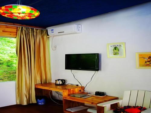 a room with a desk and a television on a wall at Spring Flowers Blossoming Hotel in Yangshuo