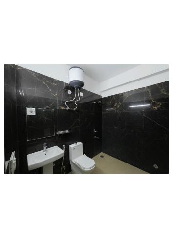 un baño con inodoro y lavabo en Hotel Stayzzy Bloom, en Noida