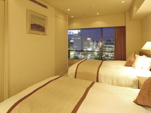 a hotel room with two beds and a window at Hotel Harvest In Yonago in Yonago