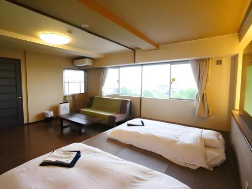 a bedroom with a bed and a couch and a window at Green Hotel Yes Nagahama Minatokan in Nagahama