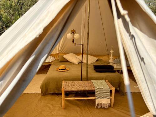 a bed in a tent with a hat on it at Quinta da Paz Eco-Lodge in São Luis