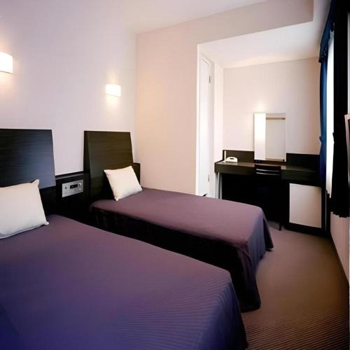 a hotel room with two beds and a desk at Hirata Maple Hotel in Izumo