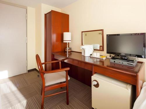 a room with a desk with a television and a chair at Fukuyama Terminal Hotel in Onomichi
