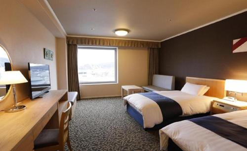 a hotel room with two beds and a television at Green Hill Hotel Onomichi in Onomichi
