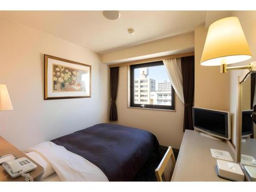 a hotel room with a bed and a desk with a phone at Albert Hotel in Akita