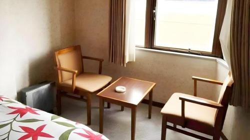 a room with two chairs and a table and a bed at Sento Otani Hotel in Toyooka