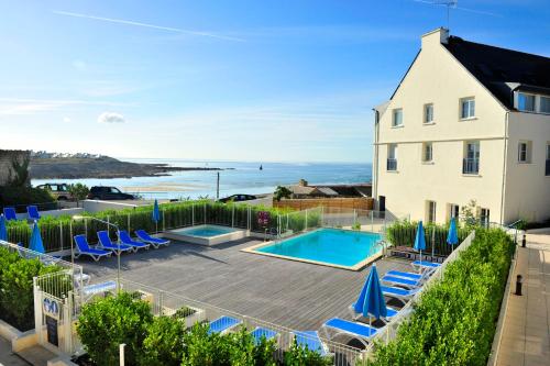 a house with a swimming pool and blue lounge chairs at Résidence Goélia An Douar in Audierne