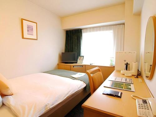 a room with a bed and a desk with a computer at Kushiro Royal Inn in Kushiro