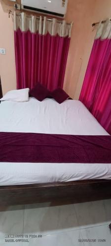 a bedroom with a large bed with purple curtains at Hotel Aishwarya New Digha I Near Amrabati Park in Digha